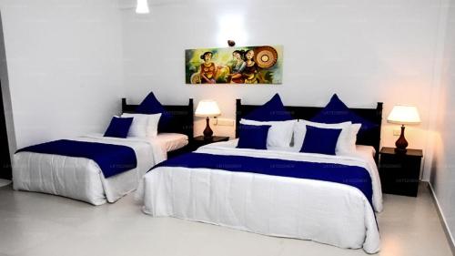 a bedroom with two beds with blue and white pillows at Blue Spring Hotel Wadduwa in Wadduwa
