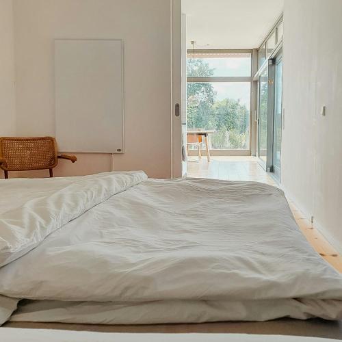 a white bed in a room with a large window at Natural Wooden House With Panoramic View in Ihlow