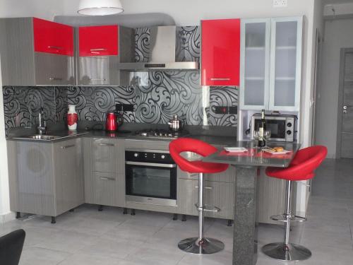 uma cozinha com armários vermelhos e bancos de bar vermelhos em Penthouse next to the beach em Marsaskala