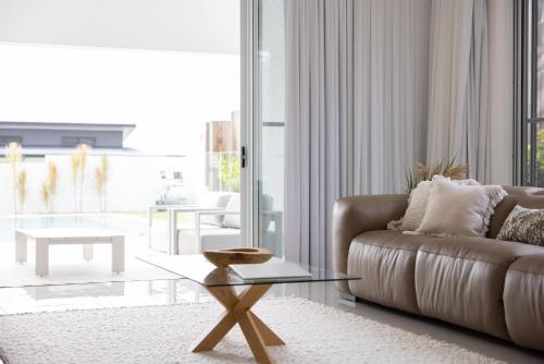 a living room with a couch and a glass table at Stylish 4-Bed Home with Pool Near Coolum Beach in Coolum Beach