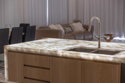 a kitchen with a sink and a living room at Stylish 4-Bed Home with Pool Near Coolum Beach in Coolum Beach