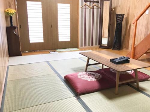 a living room with a table and a red pillow at 一棟貸しの宿　松江の里 in Matsue