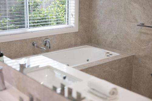 a bathroom with a bath tub and a window at Stylish 4-Bed Home with Pool Near Coolum Beach in Coolum Beach