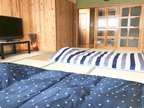 a bedroom with two beds and a flat screen tv at 一棟貸しの宿　松江の里 in Matsue