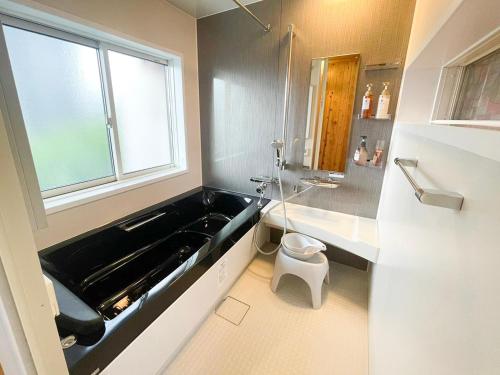 a bathroom with a black bath tub and a window at 一棟貸しの宿　松江の里 in Matsue