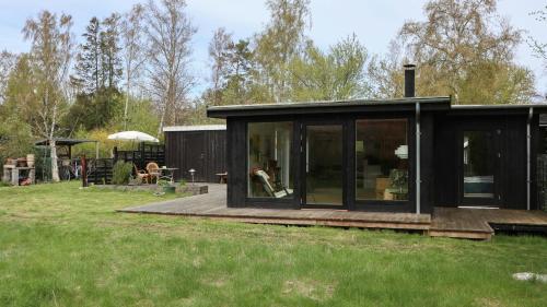 une maison noire avec terrasse dans l'herbe dans l'établissement Summer House Charm Near Hårbølle Havn, à Askeby