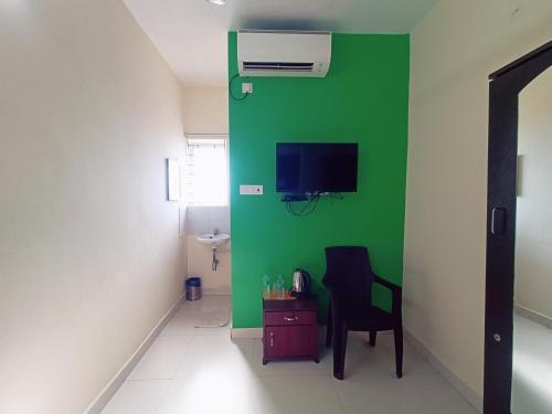 a green wall in a room with a chair and a tv at Green Tree Hotel-Near VFS Global and Ramee Mall in Chennai