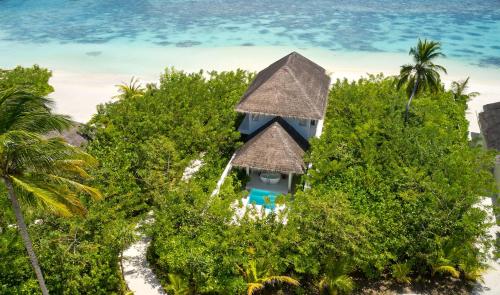 an island with a house in the middle of trees at Sun Siyam Iru Veli - 24 Hours Premium All-Inclusive with Free Transfers in Dhaalu Atoll