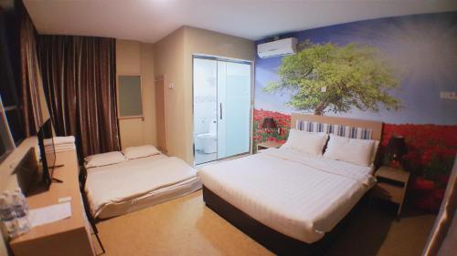 a hotel room with two beds and a window at Om Hotel in Simpang Ampat