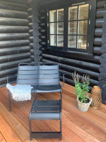 a black chair sitting on a porch with a plant at Nordic Exclusive Log House On The North Coast in Tisvildeleje