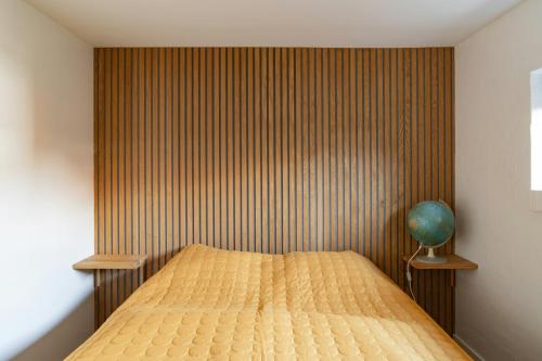 a bedroom with a bed with a wooden wall at Modern Exclusivity In 60S House Near Dyngby Beach in Odder
