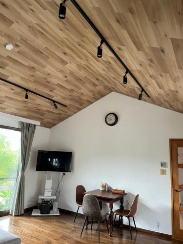 a room with a wooden ceiling with a table and chairs at 笠神庵 in Tagajo