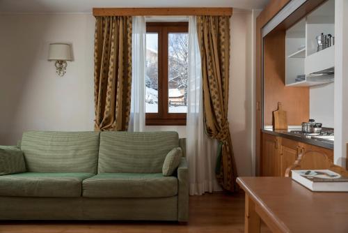 a living room with a green couch and a window at Hotel Residence 3 Signori in Santa Caterina Valfurva