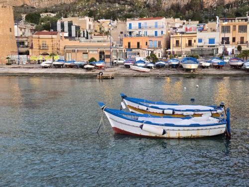 two boats are docked in the water near a city at Finestra sul Golfo in Mondello