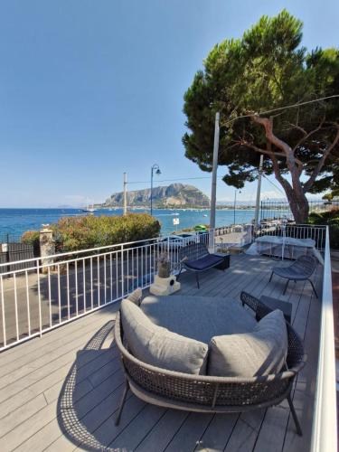 a deck with a couch and chairs on the beach at Finestra sul Golfo in Mondello