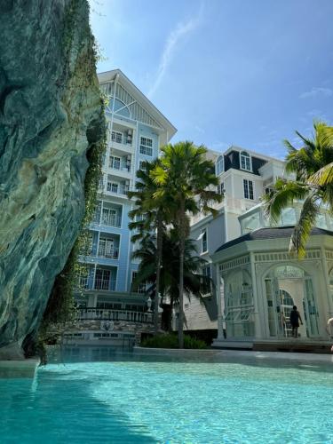 a building with a swimming pool in front of a building at Grand Florida Beach Front Pattaya in Na Jomtien