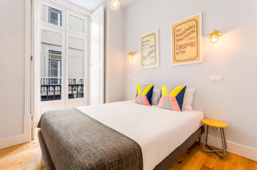a bedroom with a large white bed with colorful pillows at Casas da Baixa - Lighthouse Apartments in Lisbon