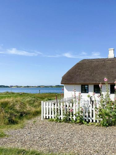a white house with a white picket fence and flowers at Historic House With Fjord View On Venø in Venø By