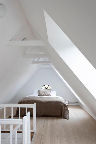 a white bedroom with a bed in a attic at Artistic Gardener's House At Kollerup Estate in Hadsten Stationsby