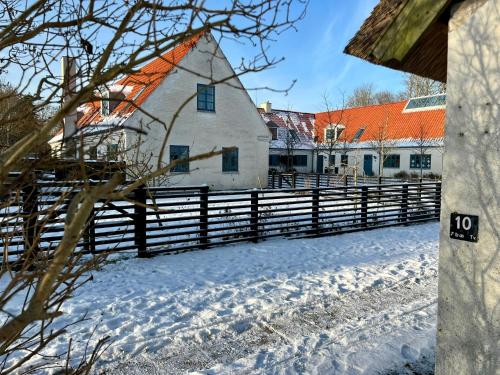 a barn in the snow with a fence at Historic Farm Atmosphere In Tisvildeleje in Tisvilde