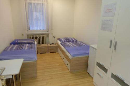 a room with two beds and a desk and a window at Montagehotel Bed & Steel in Linz