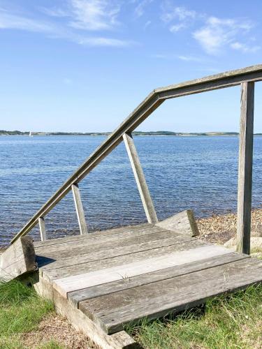 a wooden bench sitting next to a body of water at Historic House With Fjord View On Venø in Venø By