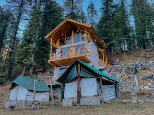 a tree house with a balcony on top of it at Singing Woods Kutla in Kulu