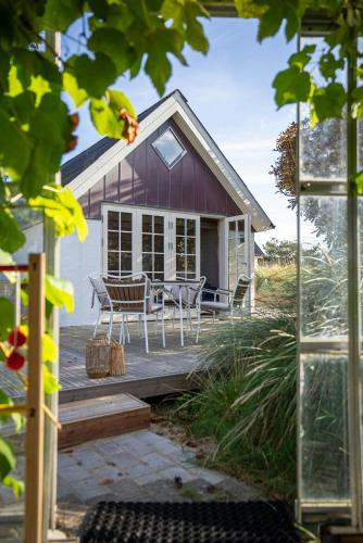 a house with a table and chairs on a deck at Historic Fisherman's Gem With Twist In Klitmøller in Torsted