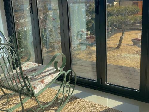 a green bench sitting in front of a window at Sarah's Small Garden in Cheonan