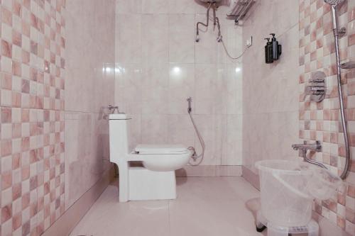a white bathroom with a toilet and a shower at Mount Queens Hill Resort & Spa in Mirik