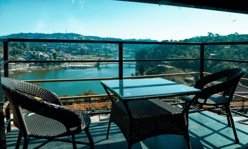 a table and chairs on a balcony with a view of a river at Mount Queens Hill Resort & Spa in Mirik