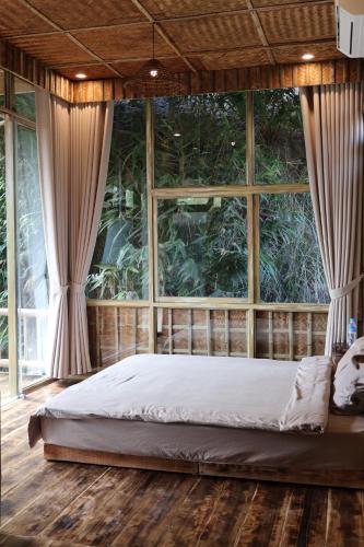 a bed in a room with a large window at Dinh Gia Trang - Homestay & Coffee in Yên Bái