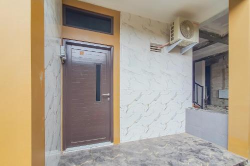a brown door on the side of a house at Urbanview Aurel House Cirebon in Plered