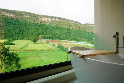 a bathroom with a bath tub and a large window at Viewpoint Khaoyai Hotel in Mu Si