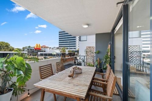 a balcony with a wooden table and chairs at Crown Beach Escape - Stylish Comfort by the Sea in Wollongong