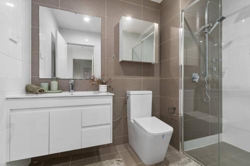 a bathroom with a toilet and a glass shower at Crown Beach Escape - Stylish Comfort by the Sea in Wollongong