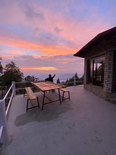 a man sitting at a picnic table on a patio at Simba Jungle Lodge, Binsar Wildlife Sanctuary in Binsar
