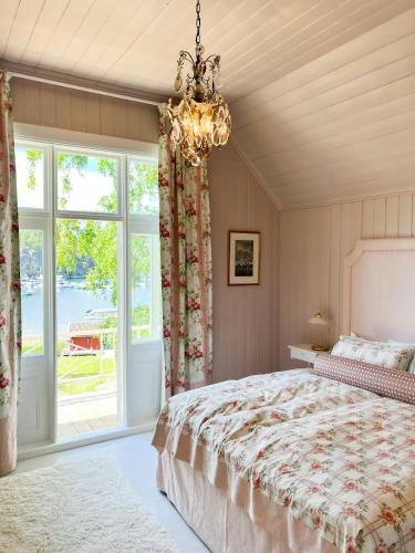 a bedroom with a large bed and a chandelier at Charming Swiss-Style Cabin On Hankø in Gressvik