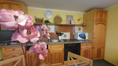 a kitchen with wooden cabinets and pink flowers at Blütenhaus im Rhododendronpark 5 min zum See in Kromlau