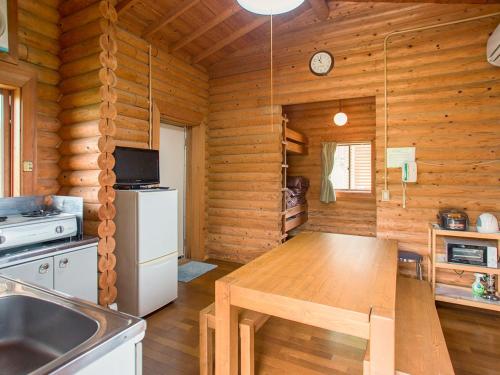 a kitchen with a table in a wooden cabin at コテージアンドバーベキュー 上の台緑の村 in Mori