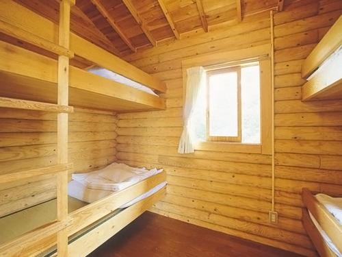 a log cabin with a bed and a window at コテージアンドバーベキュー 上の台緑の村 in Mori