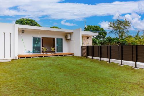 een wit huis met een grote tuin bij 美ら海水族館まで車で5分 広い庭 最大10名 まるまる貸し切り 花の雲 in Motobu