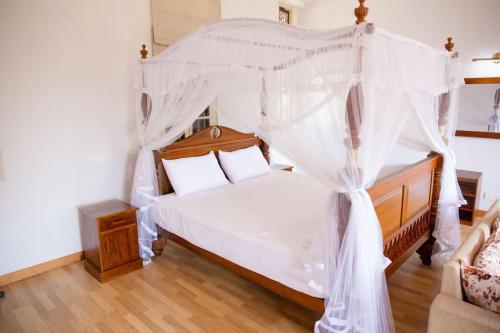 a bedroom with a canopy bed with white curtains at Adaaran Villa Bolgoda in Moratuwa