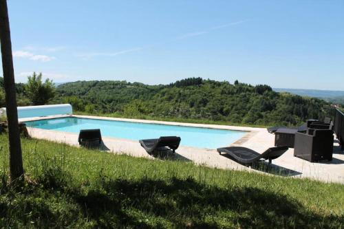 - une piscine entourée d'un groupe de chaises dans l'établissement Gîte de France à Altillac 4 épis - Gîte de France 8 personnes MAE-0731, à Altillac