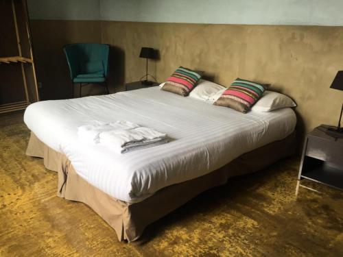 - une chambre avec un grand lit blanc et une chaise bleue dans l'établissement Gîte de France à Altillac 4 épis - Gîte de France 8 personnes MAE-0731, à Altillac