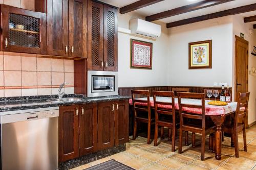 a kitchen with wooden cabinets and a table with chairs at Casa Rural Arroal I in Sotoserrano
