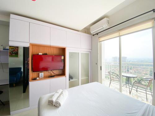 Un dormitorio con una cama blanca y una ventana grande. en Best Choice and Modern Studio at Mataram City Apartment By Travelio, en Kejayan