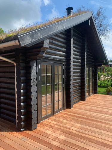 a log cabin with glass doors on a wooden deck at Nordic Exclusive Log House On The North Coast in Tisvildeleje