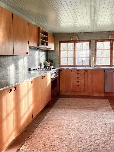 a large kitchen with wooden cabinets and a rug at Authentic 60S Gem In Rø Near Gudhjem in Gudhjem
