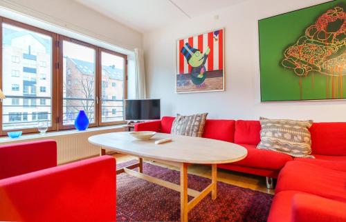 a living room with a red couch and a table at Spacious Canal-View Apartment Near Metro in Christianshavn in Copenhagen